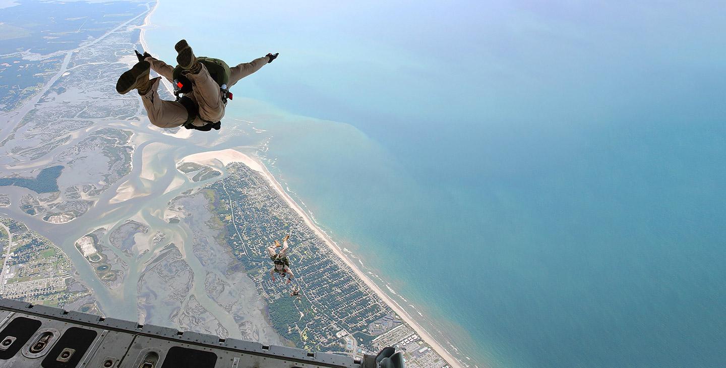 Warfighters with parachutes jumping out the back of a C-17 aircraft equipped with aircraft technology 